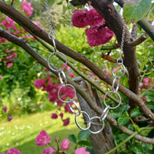 Load image into Gallery viewer, Sterling silver necklace, made up of 11 hammered silver hoops that make up the front of the necklace, that hand on a thick sterling silver chain. This necklace is 18 inches on length and has a lobster clasp to close. It comes presented in a pretty gift box making it perfect for gift giving or storing safely. Designed and Handmade in Dingle. Hallmarked in Dublin Castle