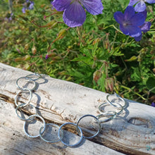 Load image into Gallery viewer, Sterling silver necklace, made up of 11 hammered silver hoops that make up the front of the necklace, that hand on a thick sterling silver chain. This necklace is 18 inches on length and has a lobster clasp to close. It comes presented in a pretty gift box making it perfect for gift giving or storing safely. Designed and Handmade in Dingle. Hallmarked in Dublin Castle