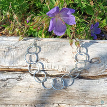 Load image into Gallery viewer, Sterling silver necklace, made up of 11 hammered silver hoops that make up the front of the necklace, that hand on a thick sterling silver chain. This necklace is 18 inches on length and has a lobster clasp to close. It comes presented in a pretty gift box making it perfect for gift giving or storing safely. Designed and Handmade in Dingle. Hallmarked in Dublin Castle