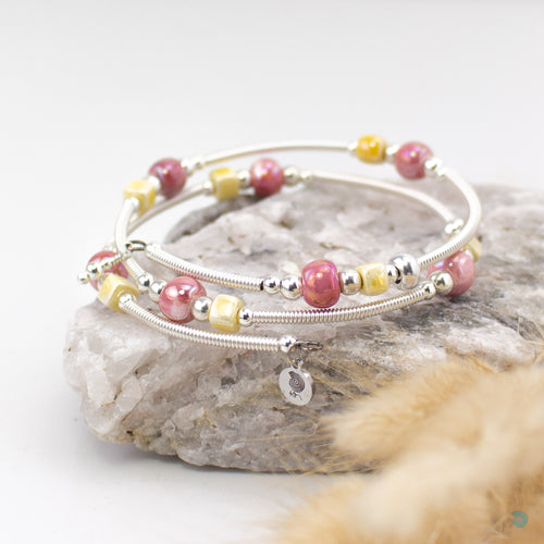 Easy to wear bracelet that simply wraps around the wrist and sits in place. No clasp needed. Hand wrapped silver filled tubes, with ceramic cubes in a yellow and dark pink  colour mix with small sterling silver beads on each side and 