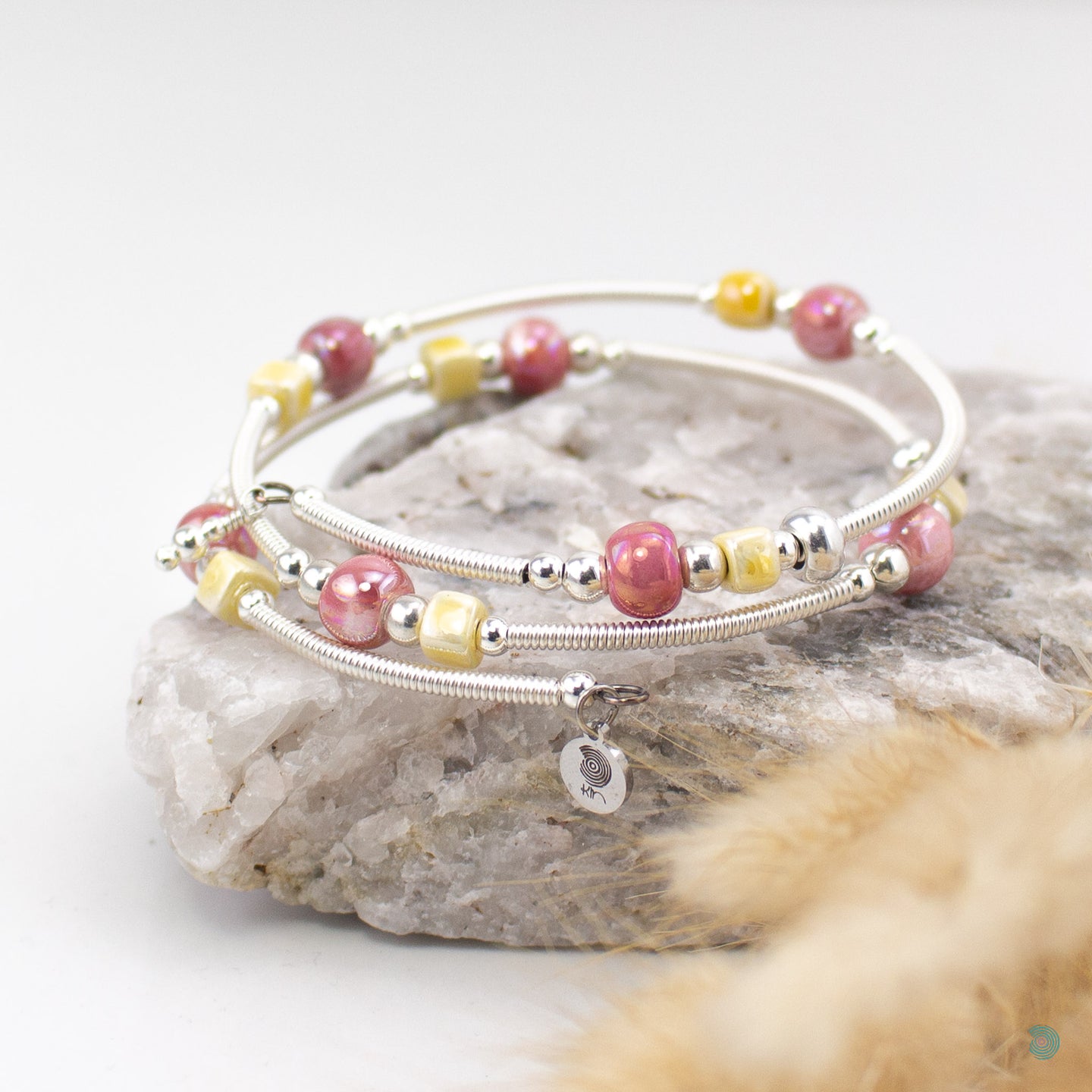 Easy to wear bracelet that simply wraps around the wrist and sits in place. No clasp needed. Hand wrapped silver filled tubes, with ceramic cubes in a yellow and dark pink  colour mix with small sterling silver beads on each side and 