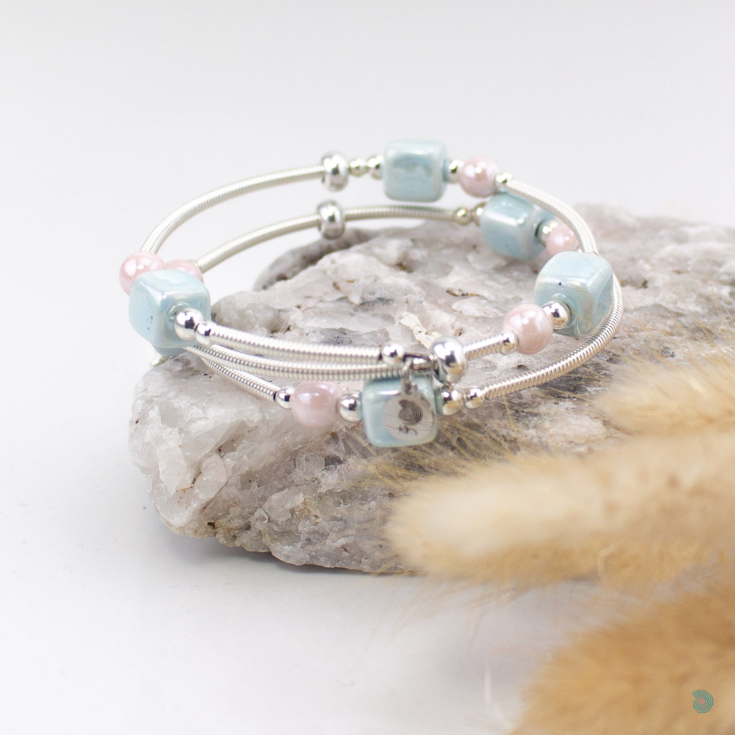 Easy to wear bracelet that simply wraps around the wrist and sits in place. No clasp needed. Hand wrapped silver filled tubes, with ceramic cubes in a pale blue and pink colour mix with small sterling silver beads on each side and 