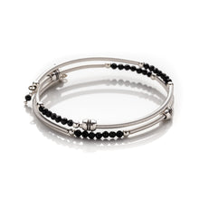 Load image into Gallery viewer, Bangle style wrap around bracelet made with hand coiled silver filled tubes with small faceted black crystals &amp; sterling silver round beads.  This bracelet features silver plated barrel beads that slide freely along the tubes. This bracelet has no clasp, it is flexible and simply wraps around the wrist and stays in place. It comes beautifully presented in an eco friendly lien gift pouch for safe keeping.  Designed &amp; Handmde in Dingle 
