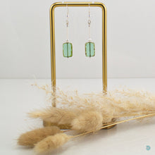 Load image into Gallery viewer, Hand wrapped silver filled drop earrings with a beautiful green Czech glass rectangular bead. These earrings sit on sterling silver ear wires and come with backs included. They are approximately 4cm in drop length from the base of the ear wires and are presented in a pretty gift pouch for safe keeping. Designed and handmade in Dingle
