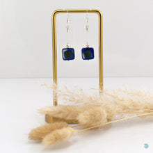 Load image into Gallery viewer, Hand wrapped silver filled drop earrings with a beautiful blue Czech glass squares. These earrings sit on sterling silver ear wires and come with backs included. They are approximately 4cm in drop length from the base of the ear wires and are presented in a pretty gift pouch for safe keeping. Designed and handmade in Dingle
