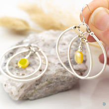 Load image into Gallery viewer, A real summer statement pair of earrings  Hand wrapped silver filled double hoops with vibrant yellow Czech glass square centre beads.  These earrings are are lightweight and approximately 5cm in drop length from the base of sterling silver ear wires, they come with backs included.  They are presented in a pretty gift box for safe keeping or making them perfect for gift giving  Designed and Handmade in Dingle
