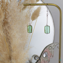 Load image into Gallery viewer, Hand wrapped silver filled drop earrings with a beautiful green Czech glass rectangular  bead. These earrings sit on sterling silver ear wires and come with backs included. They are approximately 4cm in drop length from the base of the ear wires and are presented in a pretty gift pouch for safe keeping. Designed and handmade in Dingle
