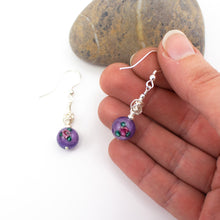 Load image into Gallery viewer, Short and Sweet Earrings with pretty purple floral lampwork glass beads and handwrapped silver filled scribble beads. Sterling silver ear wires that come with backs. They are 2.5cm in drop length from the base of the earwires and come in a pretty gift pouch for safe keeping. Designed and Handmade in Dingle
