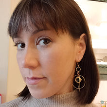 Load image into Gallery viewer, Large gold plated hoops. One large hoop with a smaller one inside, and a gold plated stainless steel square in the centre with black enamel. These earrings sit on gold plated stainless steel ear wires and come with backs included. They are approximately 5.5cm in drop length from the base of the ear wires.
