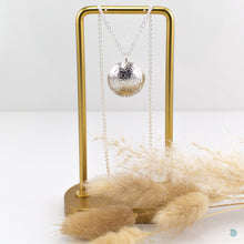 Load image into Gallery viewer, silver silver domed circular pendant with a wildflower pattern on the front. This pendant  is 2.5cm in diameter and sits on an 18 inch sterling silver chain. Hallmarked in Dublin Castle  If you would like your jewellery gift wrapped and a message added please add a little note in with your order and I will happily wrap it for you!    * Please note each pendant may have a slightly different design
