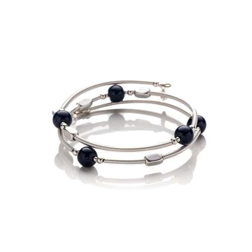 One size bangle style wrap around bracelet made from hand coiled silver filled tubes with navy blue round glass beads & sterling silver beads. This piece has silver plated rectangular beads that slide freely along the tubes. It has no clasp, it is flexible and simply wraps around the wrist and stays in place. It comes beautifully presented in an eco friendly linen gift pouch. Designed & Handmade in Dingle